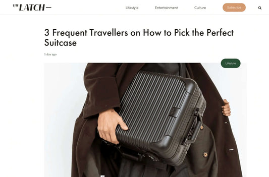 Person holding a stylish suitcase featured in The Latch article on choosing the perfect travel bag.